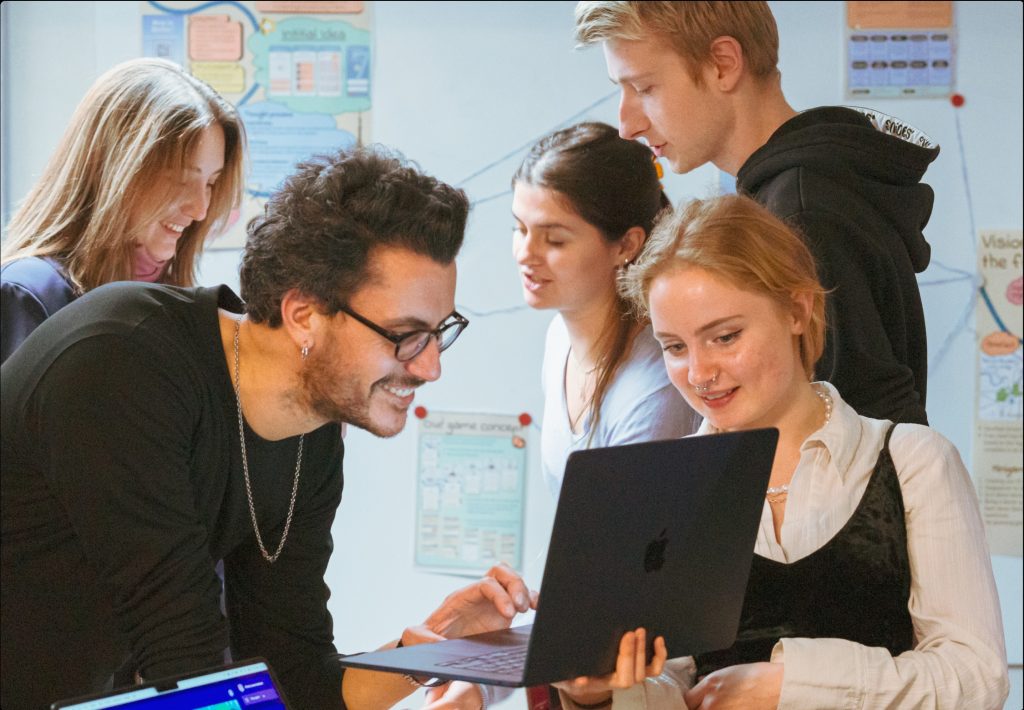 Photograph of students looking at a laptop as part of a design workshop